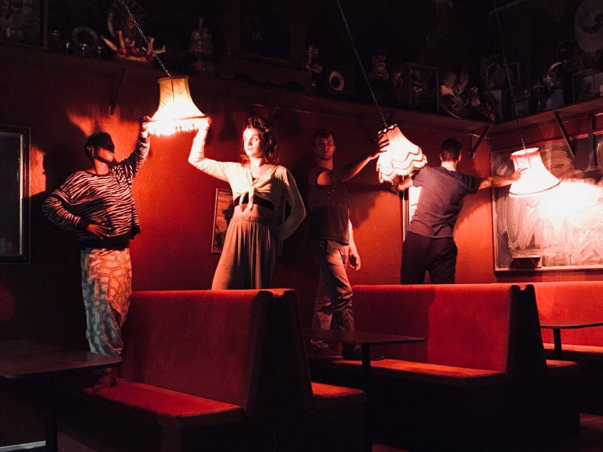 Performers standing on chairs holding table lamps