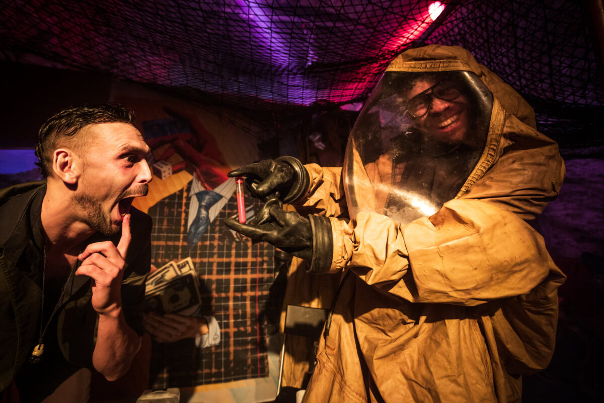 Actors in hazmat suits acting onstage