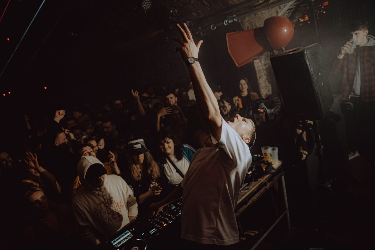 DJ performing on stage with crowd looking on