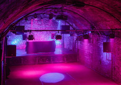an image of the tunnel 2 stage with a DJ booth on the on stage lit up with pink and purple lighting.